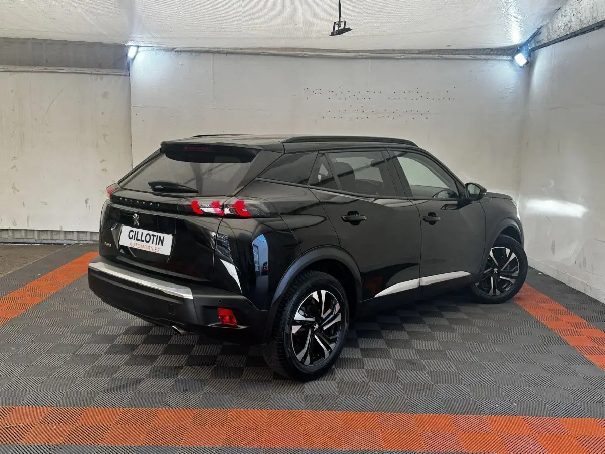 Peugeot 2008 noir vue 3/4 arrière droit dans un garage, avec jantes noires et feux arrière LED distinctifs.