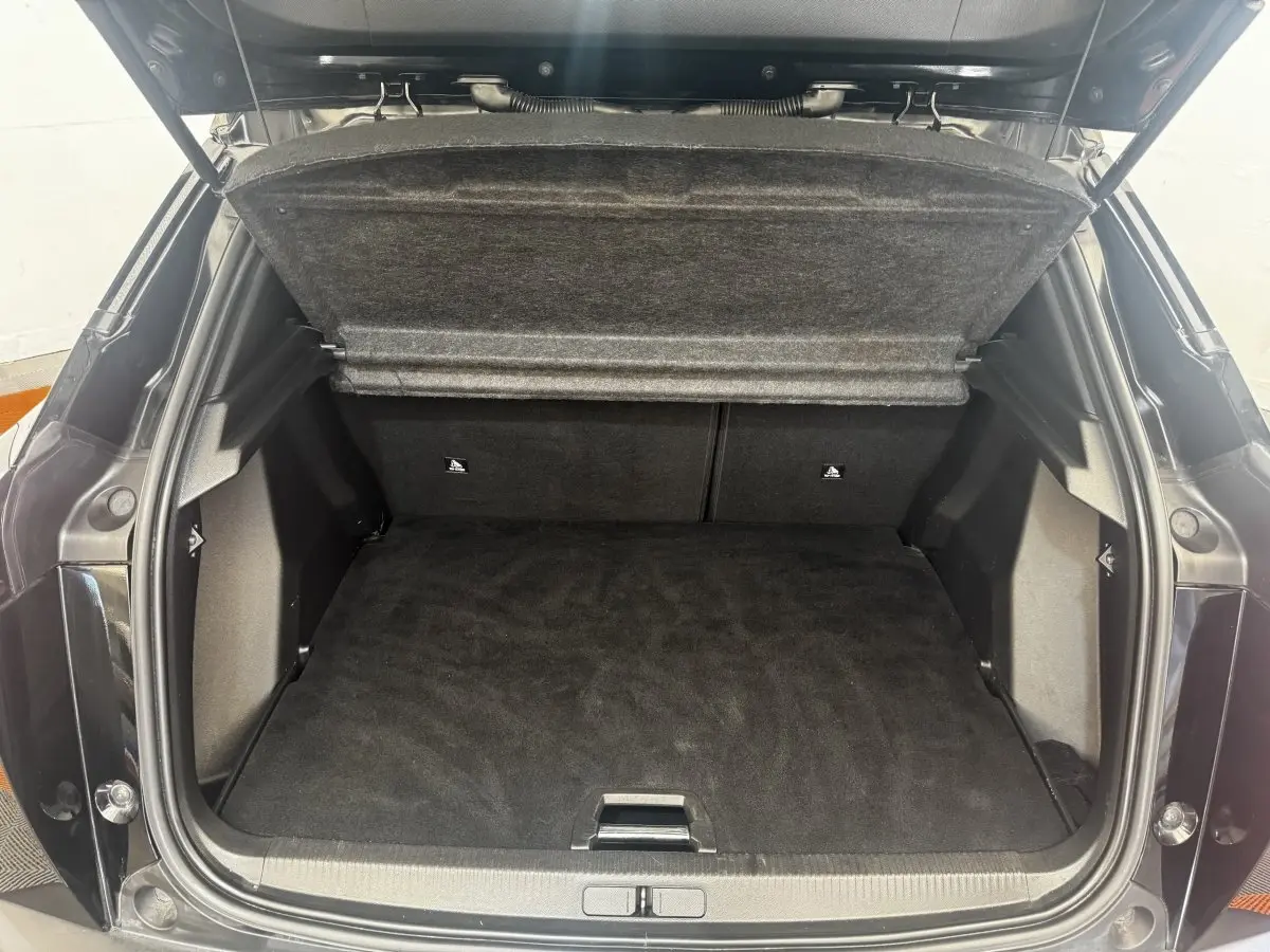 Coffre ouvert vu de l'arrière d'un Peugeot 2008 noir, montrant l'espace de chargement et la tablette cache-bagages relevée.