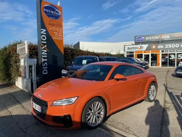 Audi TT 40 TFSI orange vue 3/4 avant droit sur parking devant concession Distinxion en 2021.