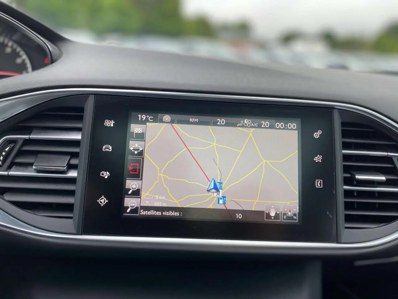 Écran tactile central de navigation allumé dans le tableau de bord d'une Peugeot 308 SW bleu magnétique, vue frontale rapprochée.