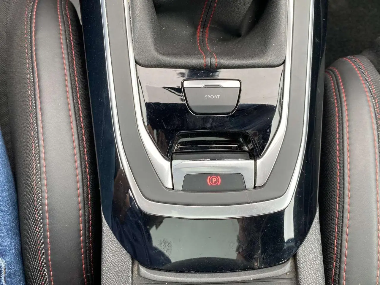 Gros plan sur la console centrale de la Peugeot 308 SW GT Line avec surpiqûres rouges et bouton mode sport.
