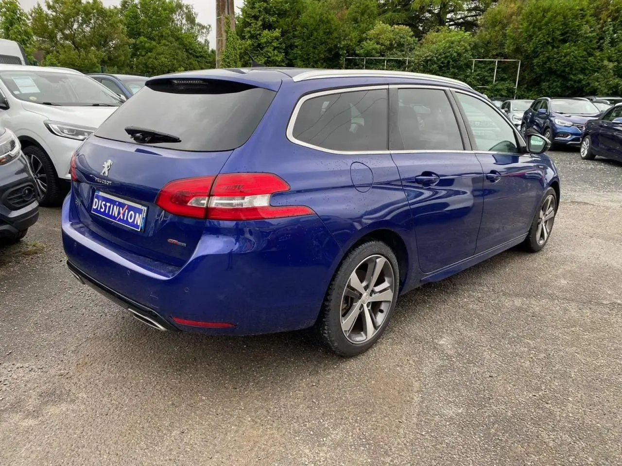 Peugeot 308 SW bleu magnétique vue 3/4 arrière droit, avec toit panoramique et jantes alliage distinctives.