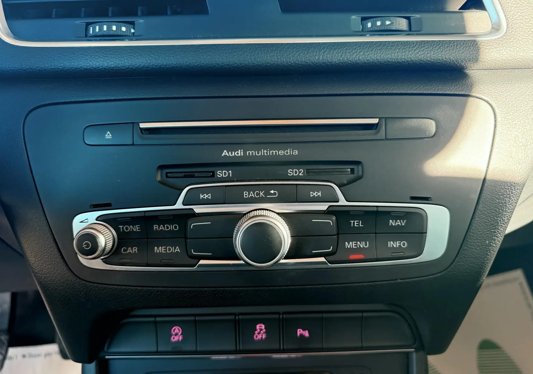 Gros plan sur la console centrale noire de l'Audi Q3 2016 avec commandes multimédia et climatisation.