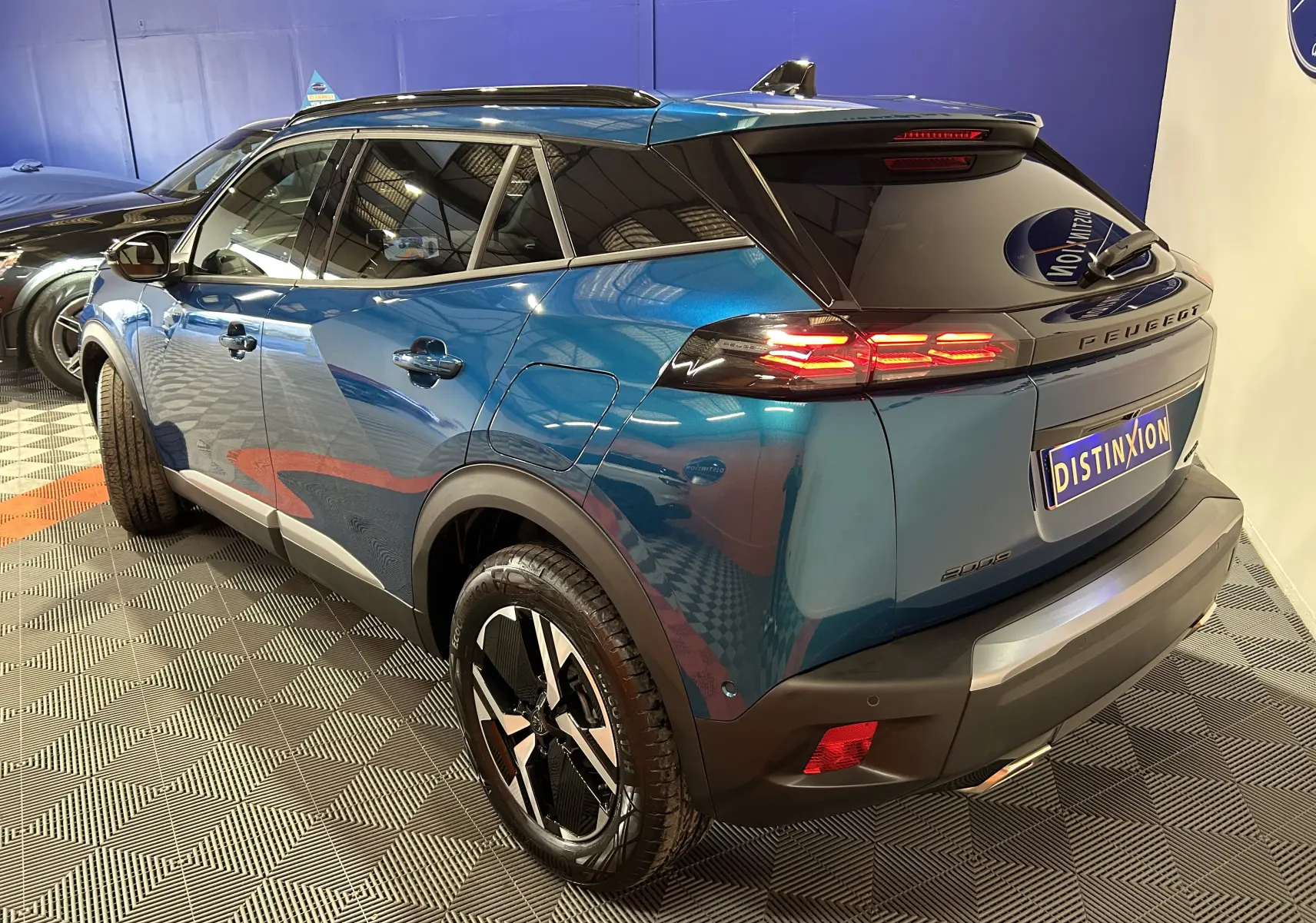 Vue 3/4 arrière droite du Peugeot 2008 bleu Obsession avec feux LED allumés et jantes noires distinctives.