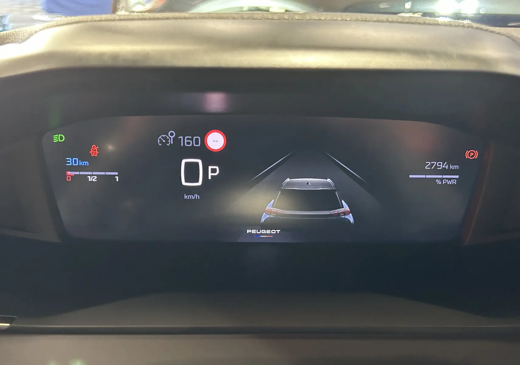 Affichage numérique du tableau de bord de la Peugeot 2008 bleu Obsession, montrant la vitesse et l'assistance à la conduite.