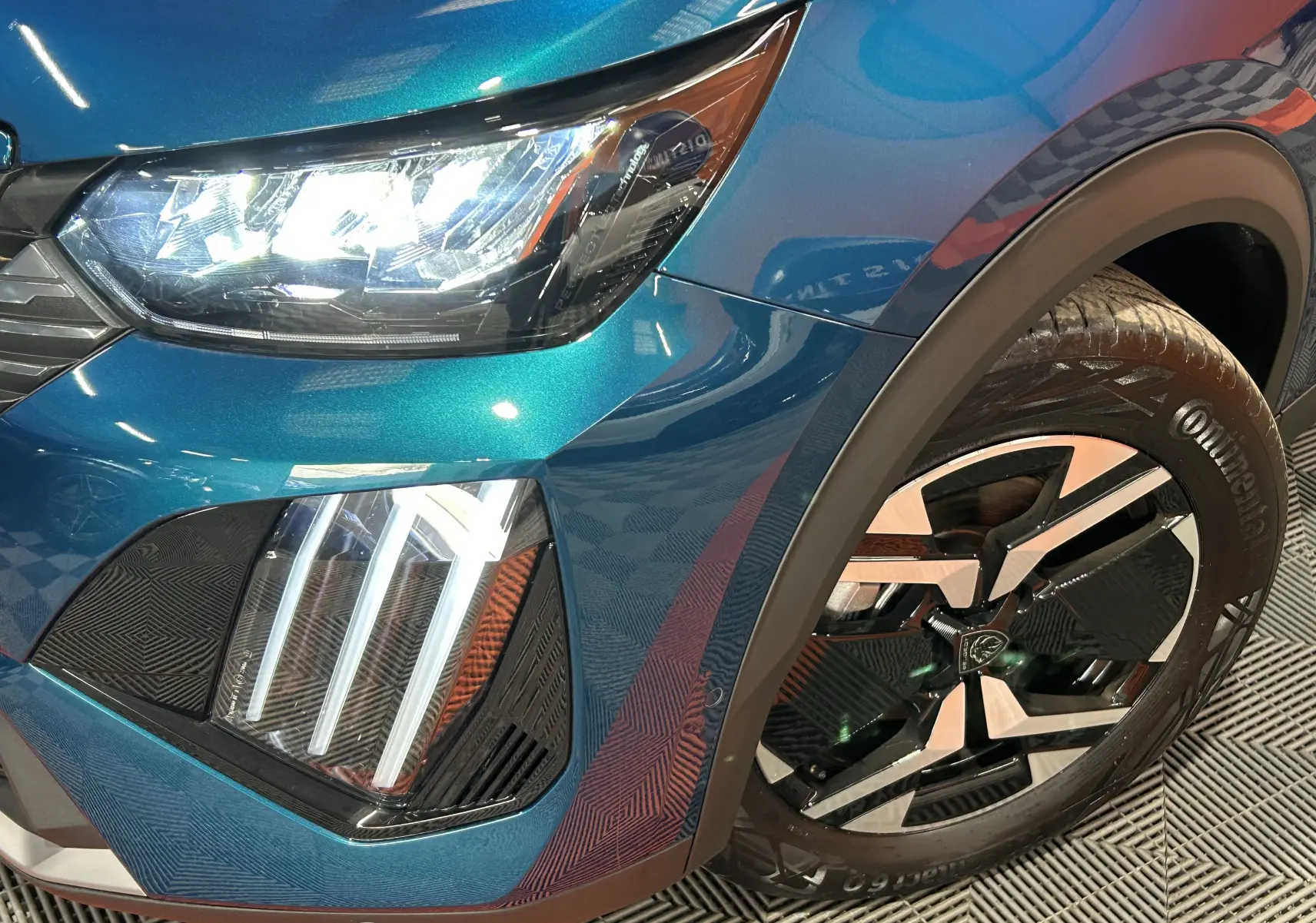 Gros plan sur l'avant droit bleu Obsession du Peugeot 2008 II Ph.2 avec phares LED allumés et jante alliage distinctive.