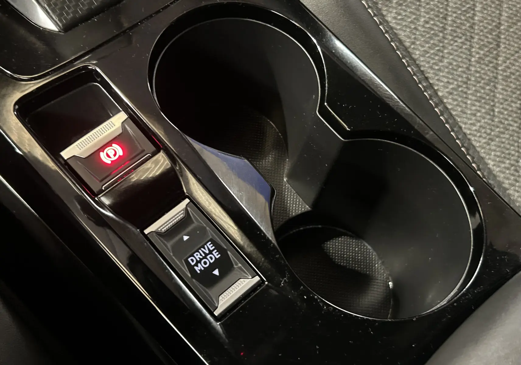 Vue rapprochée de la console centrale noire avec bouton frein à main électronique et sélection du mode de conduite Peugeot 2008.