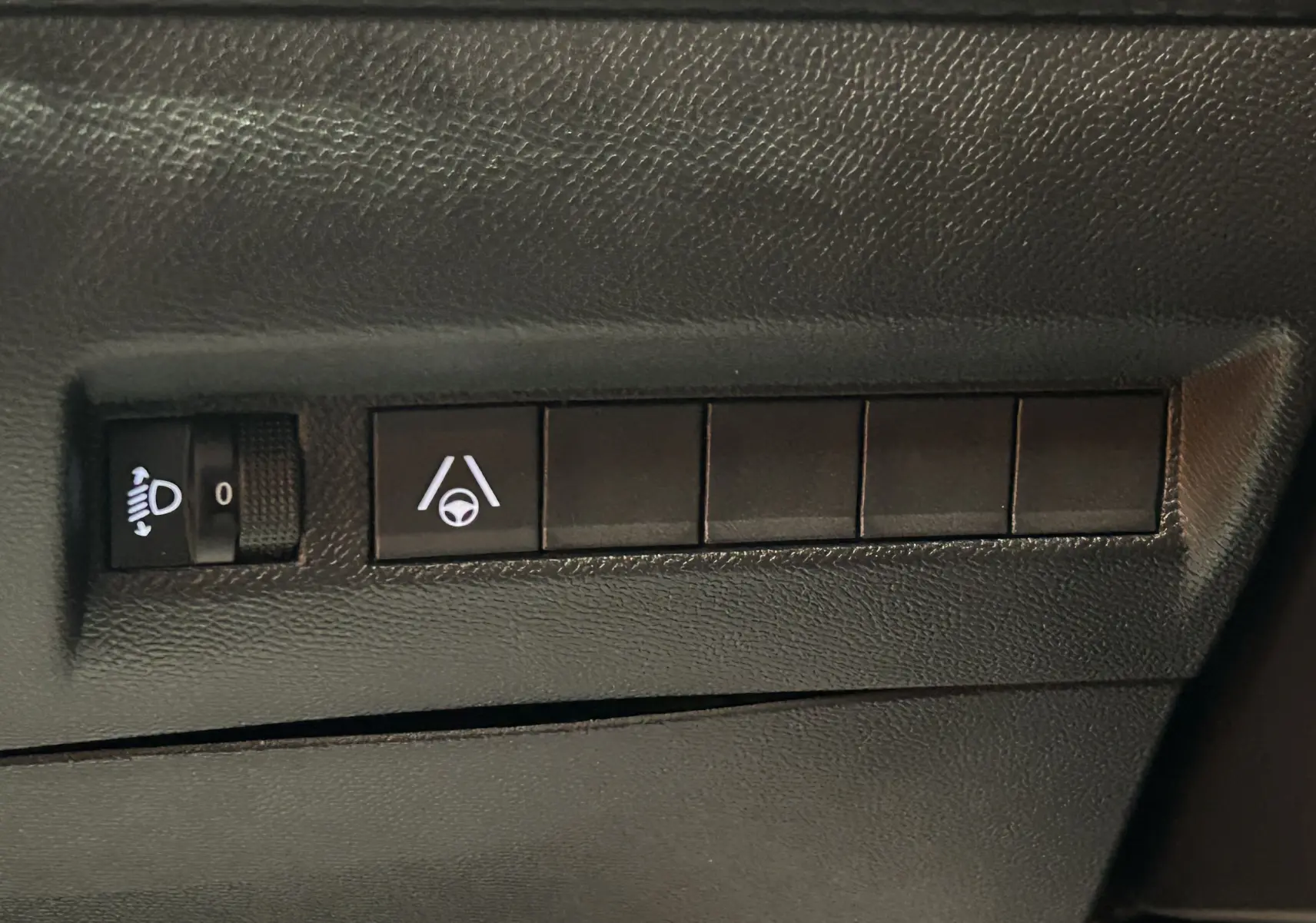 Gros plan sur les commandes de réglage des phares et d’aide au maintien de voie dans un Peugeot 2008 Bleu Obsession.