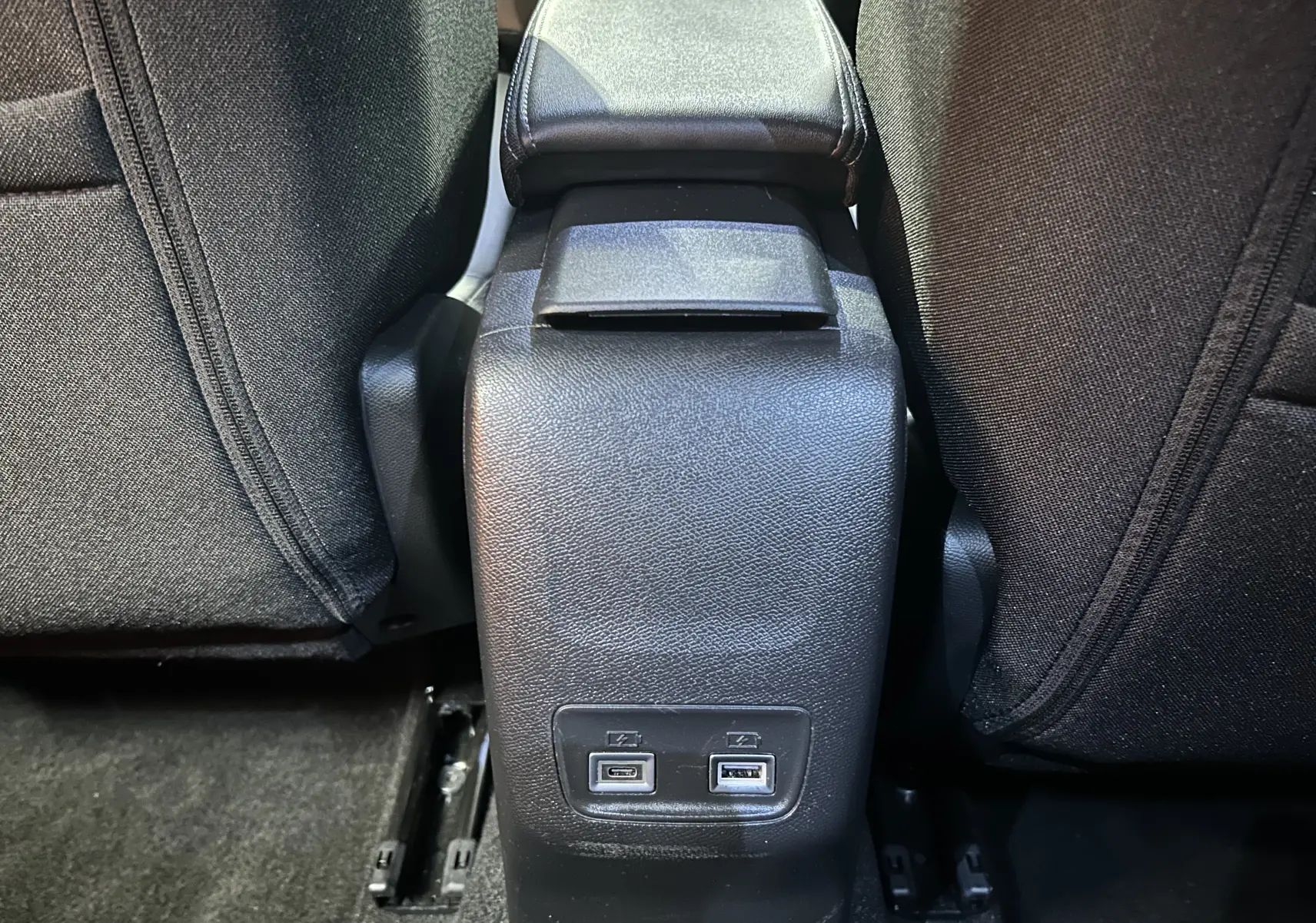 Prise USB double en bas de la console centrale arrière entre les sièges noirs du Peugeot 2008 bleu Obsession.