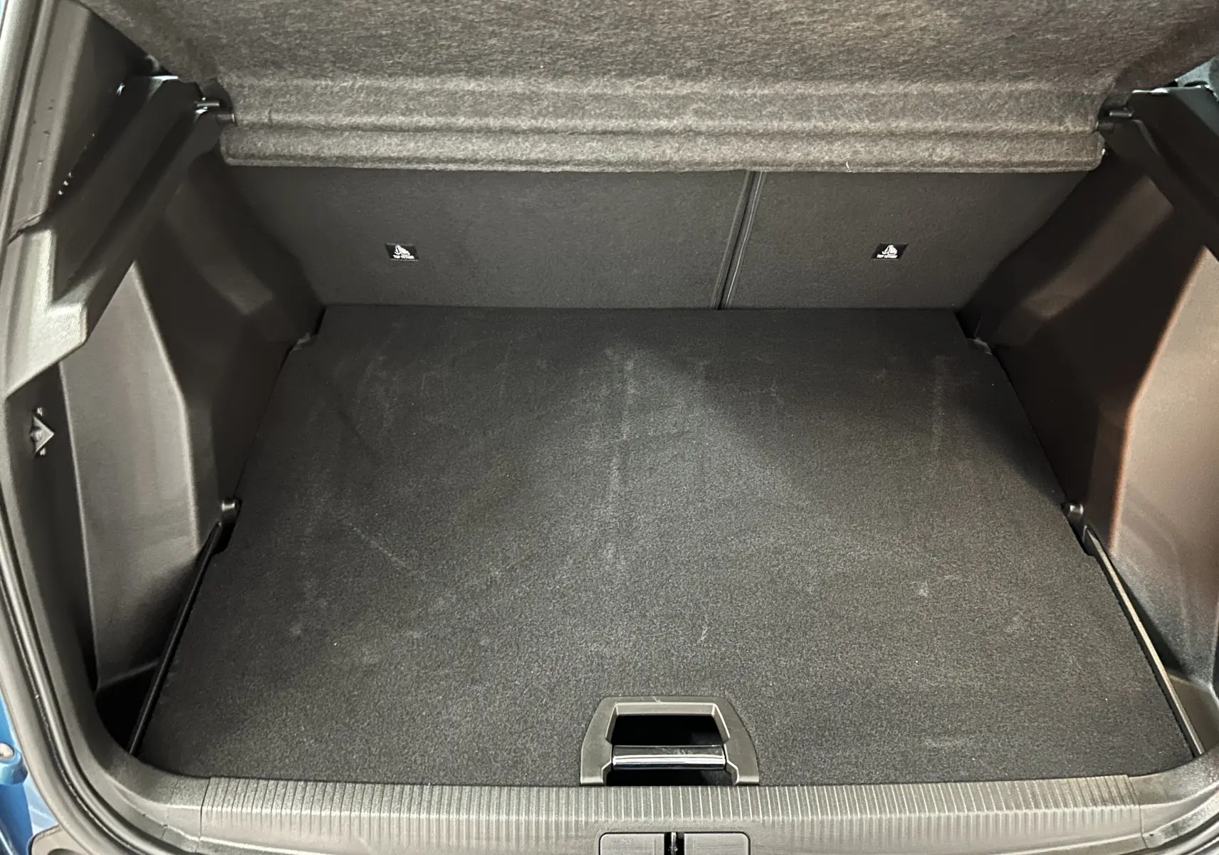 Coffre ouvert vu de face du Peugeot 2008 bleu Obsession, montrant l'espace de rangement vide et le plancher plat.