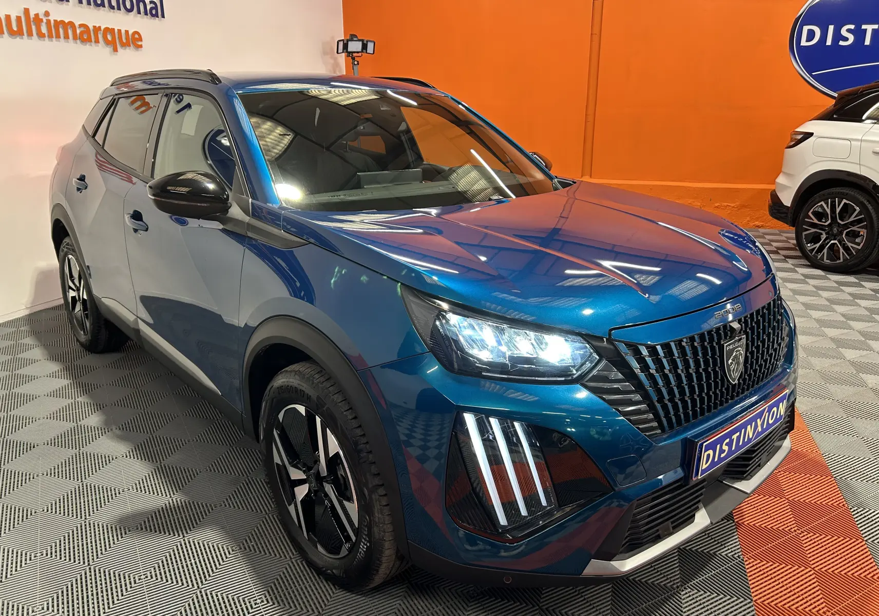 Peugeot 2008 II Ph.2 Allure Hybrid bleu Obsession, vue 3/4 avant droit avec phares LED allumés et jantes noires.