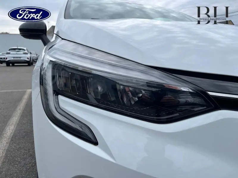 Gros plan sur le phare avant droit blanc d'une Renault Clio 1.0 TCe 100ch Business GPL 2022, avec détails LED visibles.