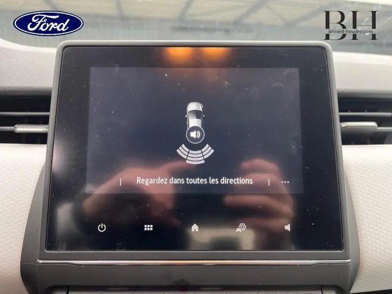 Écran tactile central d'une Renault Clio blanche, affichant une alerte de détection sonore de proximité.