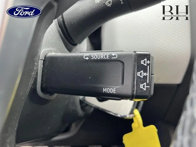 Le véhicule visible est une Renault Clio blanche vue de profil avant gauche avec becquet arrière et feux LED.