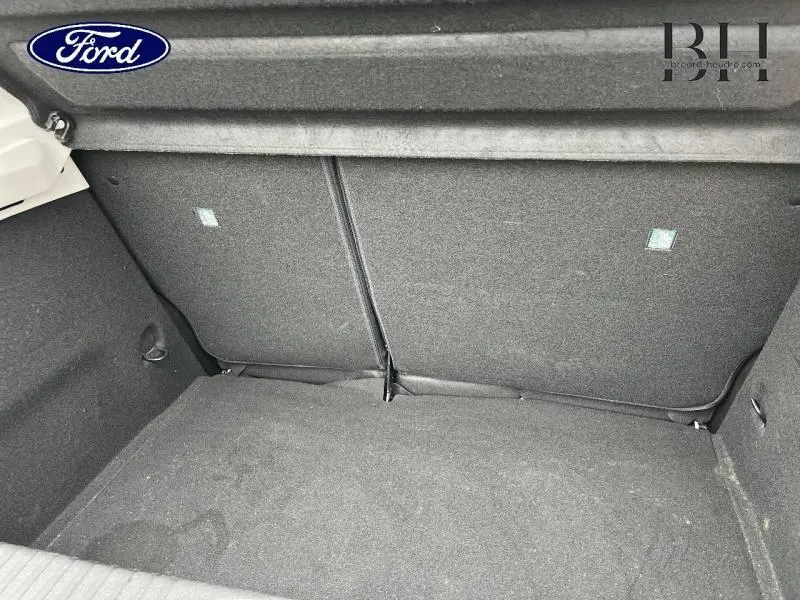 Vue intérieure du coffre vide avec banquette arrière rabattable en tissu noir sur Renault Clio blanc.