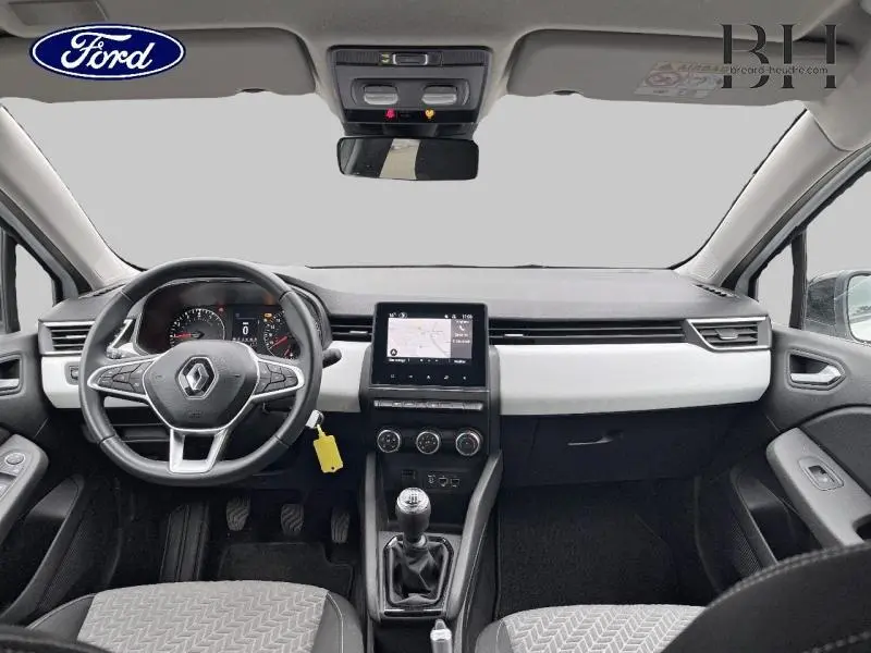 Vue intérieure avant de la Renault Clio blanche 2022, tableau de bord moderne avec écran tactile et boîte manuelle.