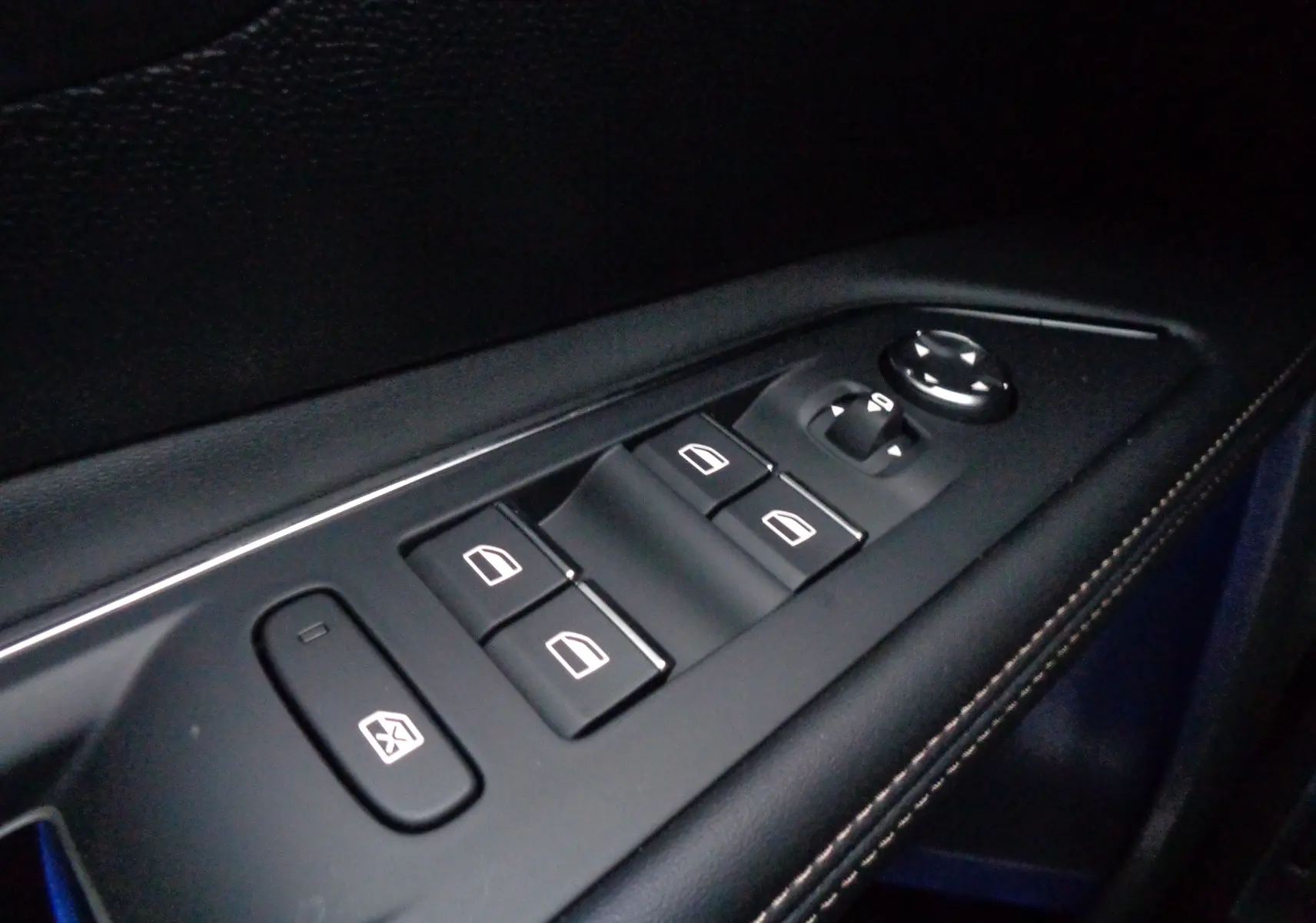 Gros plan sur les commandes des vitres électriques et des rétroviseurs sur la porte intérieure d'un Peugeot 5008 gris platinium 2023.