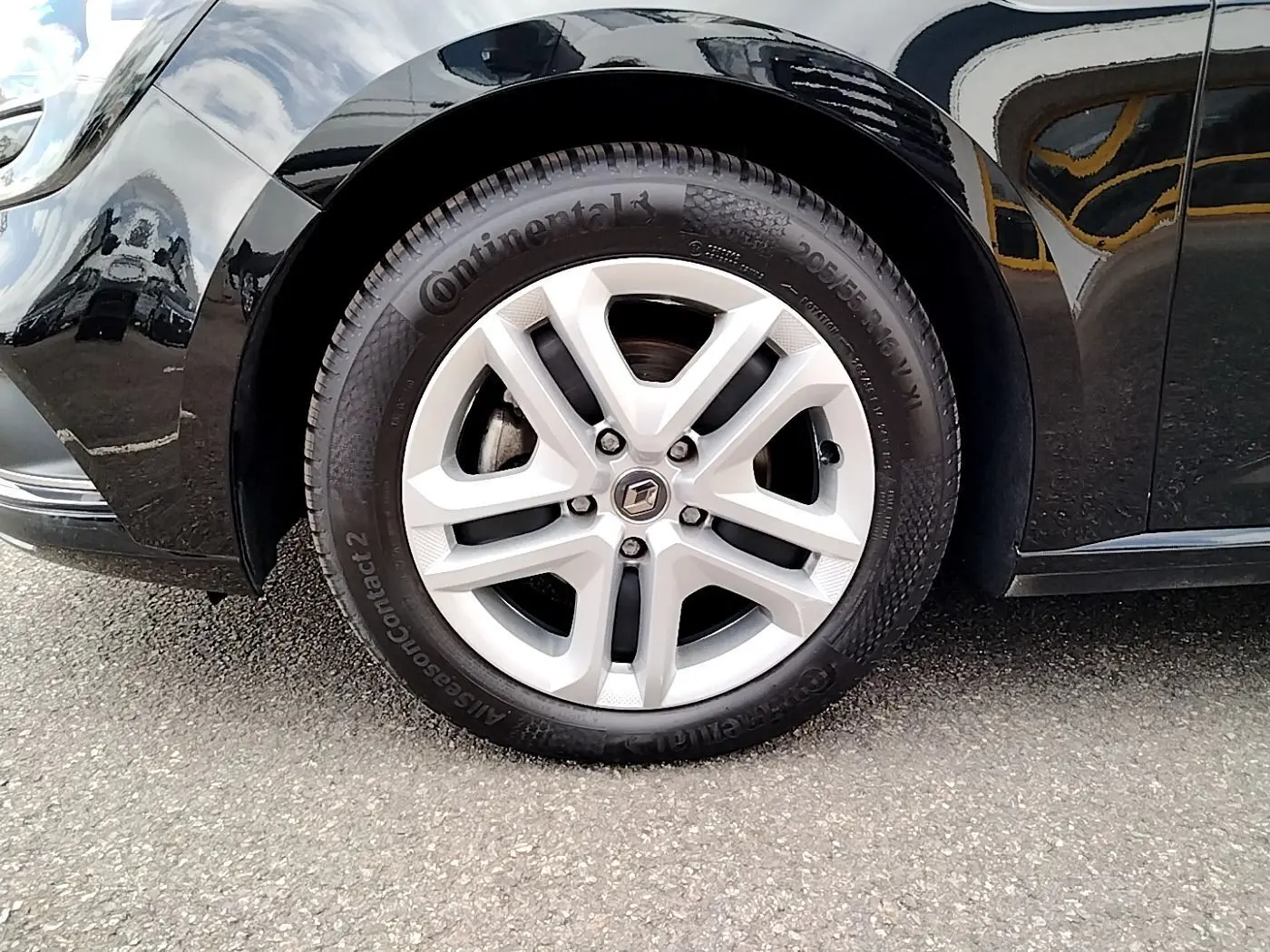 Gros plan sur la roue avant gauche noire d'une Renault Mégane IV Business TCe 140 avec jante argentée et logo Renault.