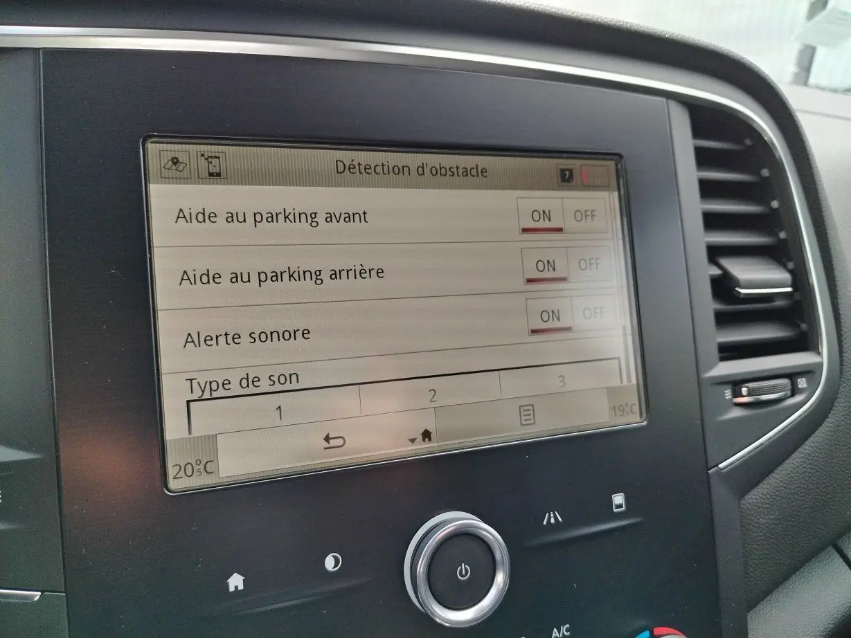 Écran tactile central de la Renault Mégane IV Business noir, affichant les réglages d'aide au parking et alertes sonores.