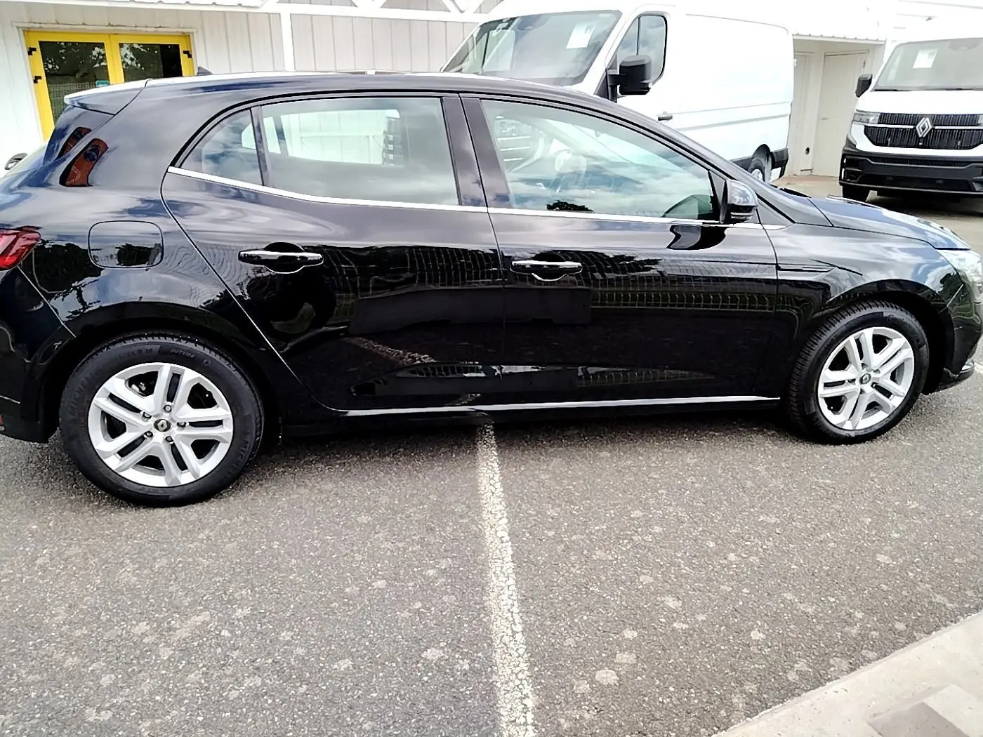 Profil côté gauche d'une Renault Mégane IV Business noire de 2020, avec jantes alliage et carrosserie brillante.