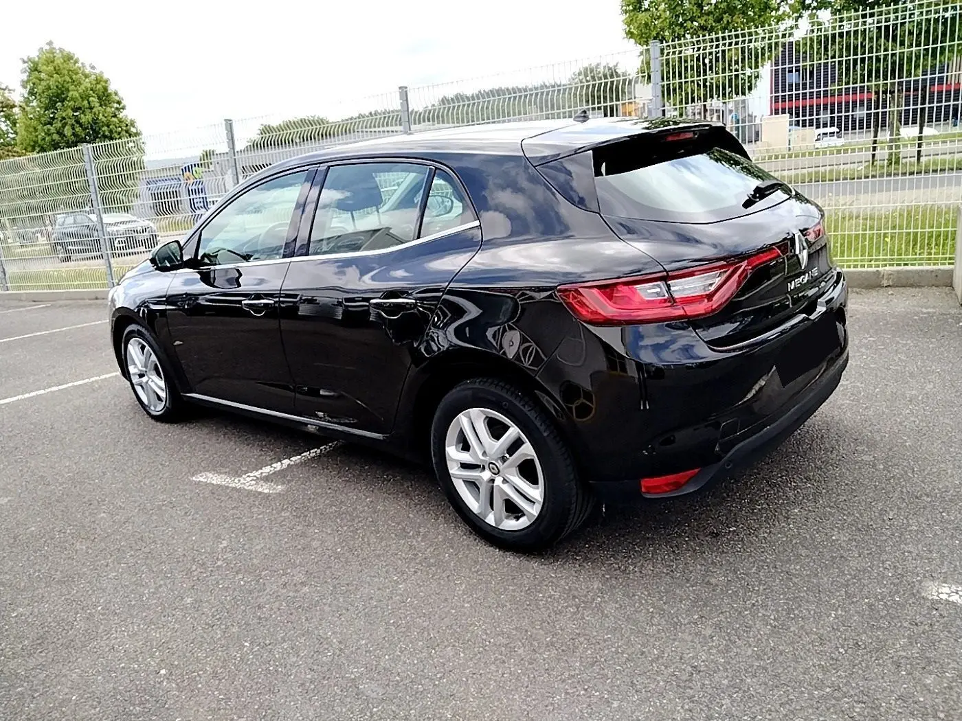 Vue 3/4 arrière droite d'une Renault Mégane IV Business noire, avec feux arrière LED et jantes argentées.