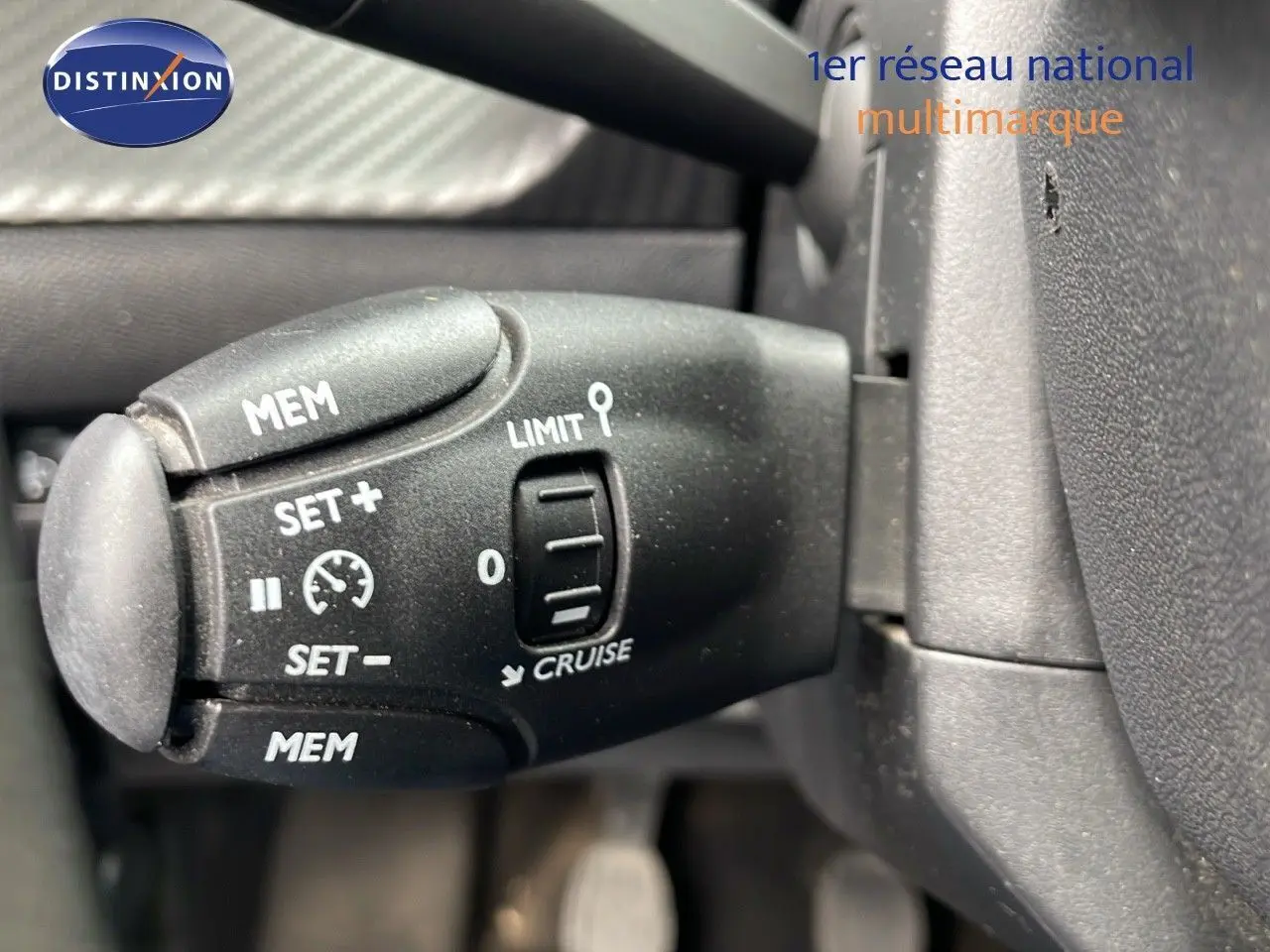 Gros plan sur la commande de régulateur de vitesse noire dans l'habitacle d'une Peugeot 208 blanche banquise.