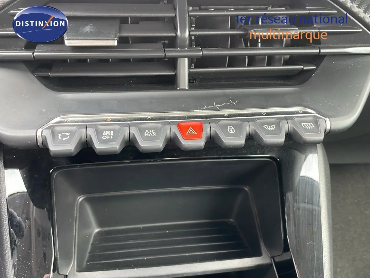 Vue rapprochée de la console centrale de la Peugeot 208 blanche, montrant les boutons de commande et les aérateurs.