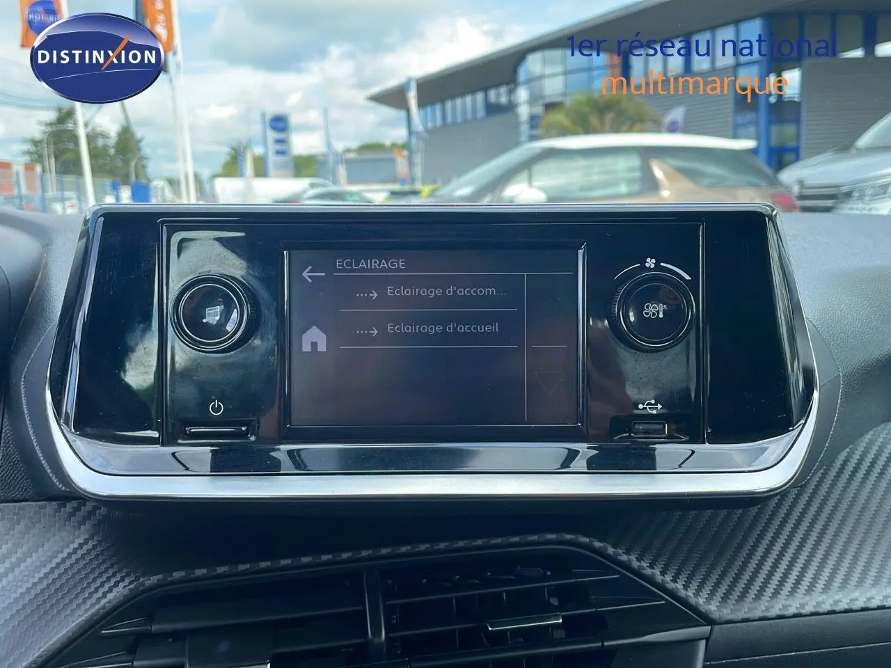 Écran tactile central du tableau de bord d'une Peugeot 208 blanche, avec commandes d'éclairage affichées.