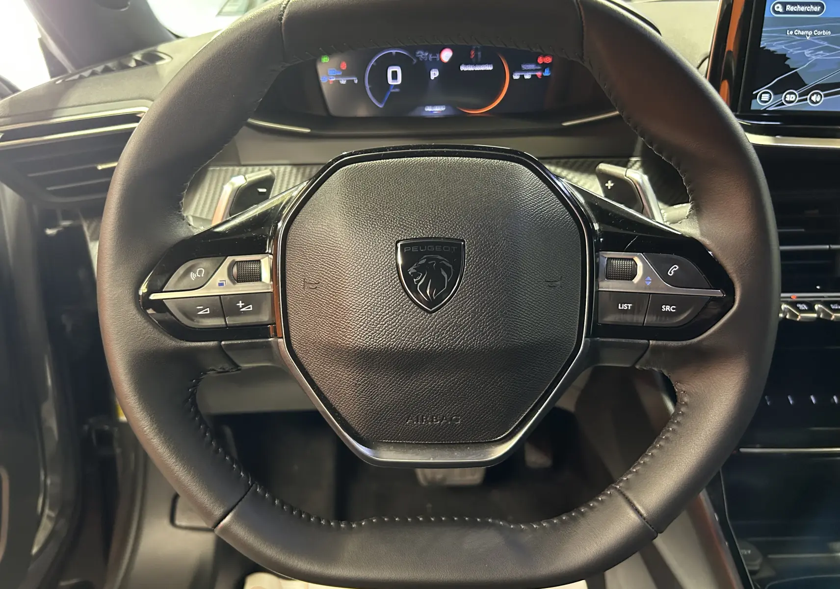 Vue rapprochée du volant cuir noir du Peugeot 2008 II Ph.2 Allure Hybrid avec commandes intégrées et tableau de bord numérique.