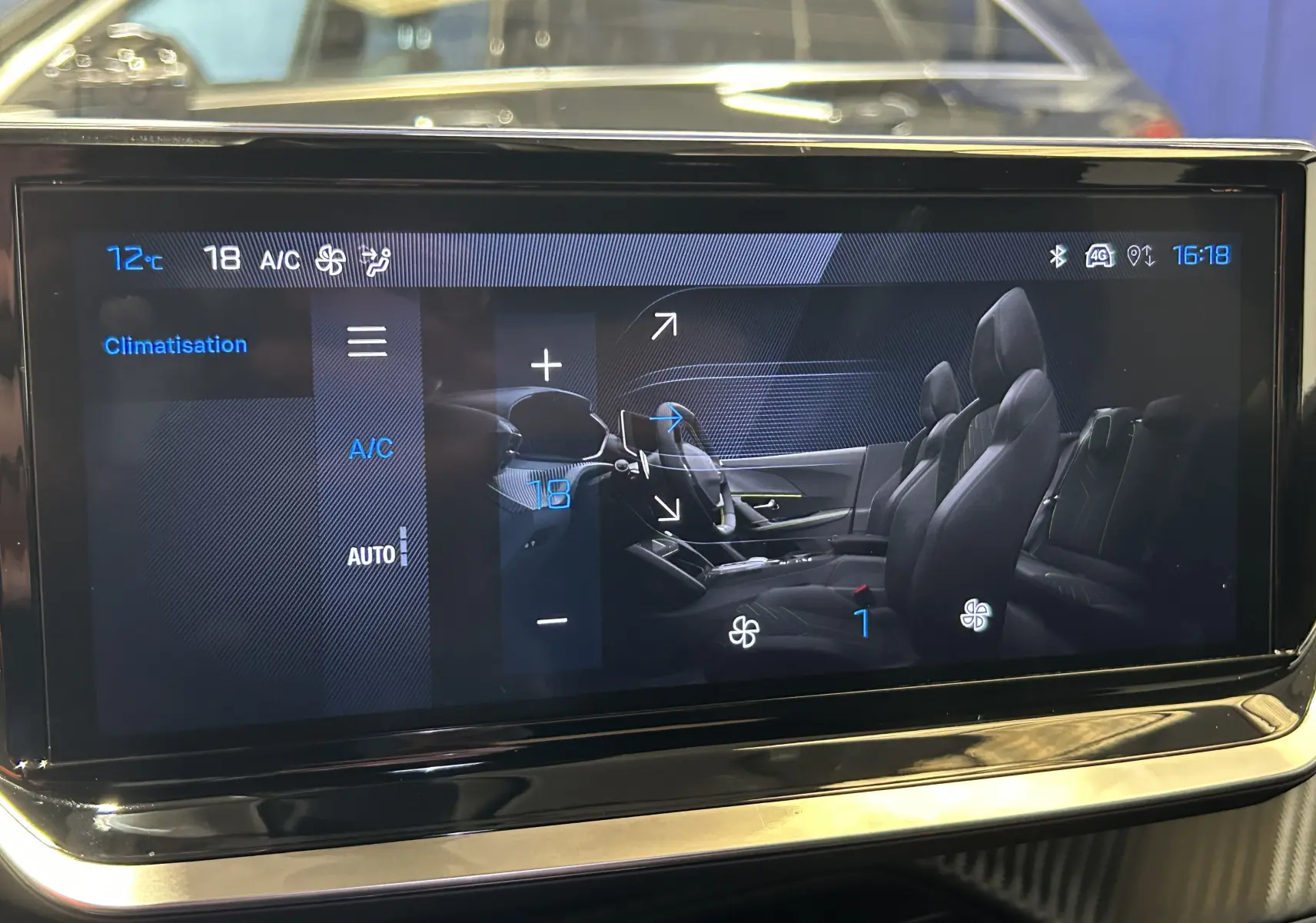Écran tactile intérieur affichant la climatisation du Peugeot 2008 II Ph.2 Allure Hybrid 145, vue latérale des sièges noirs.