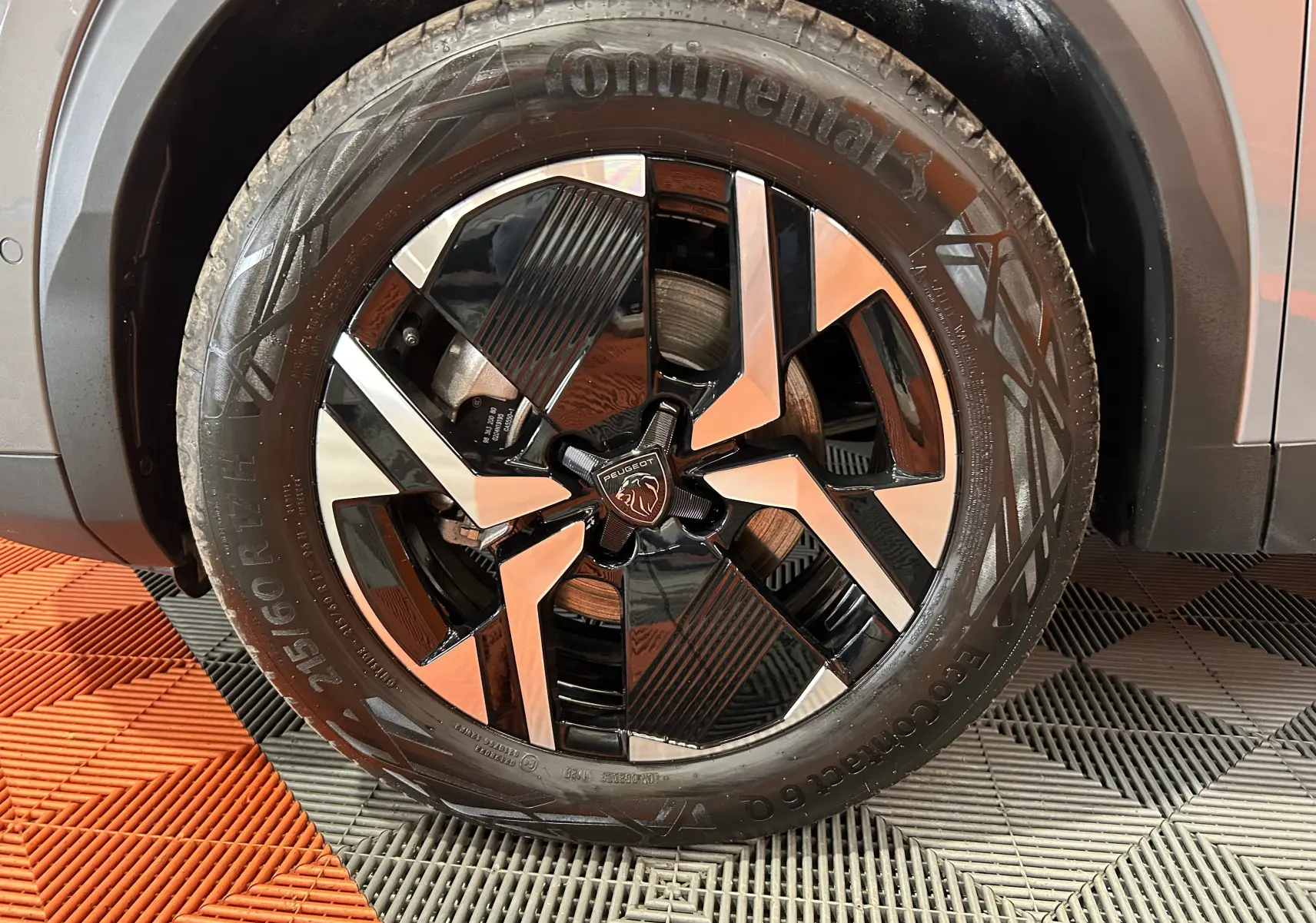 Gros plan sur la roue avant droite du Peugeot 2008 gris Selenium, mettant en valeur la jante bi-ton et le pneu Continental.