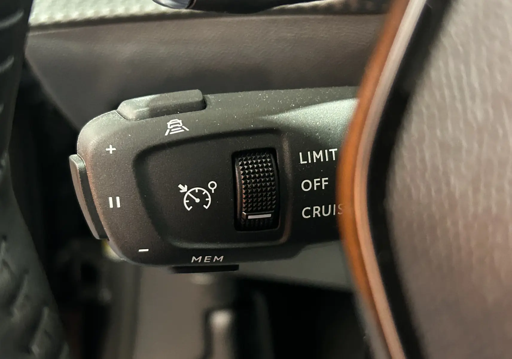 Gros plan sur la commande de régulateur de vitesse au volant d’un Peugeot 2008 gris Selenium, version hybride 2025.