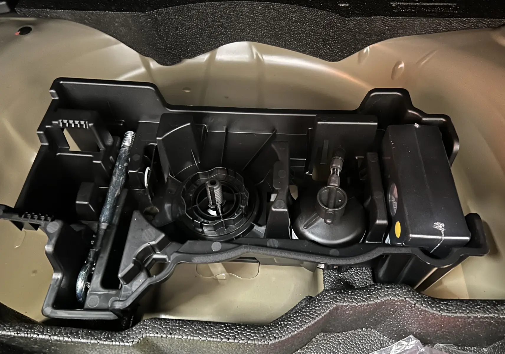 Gros plan sur le kit de dépannage pneumatique dans le coffre du Peugeot 2008 gris Selenium, vue de dessus.