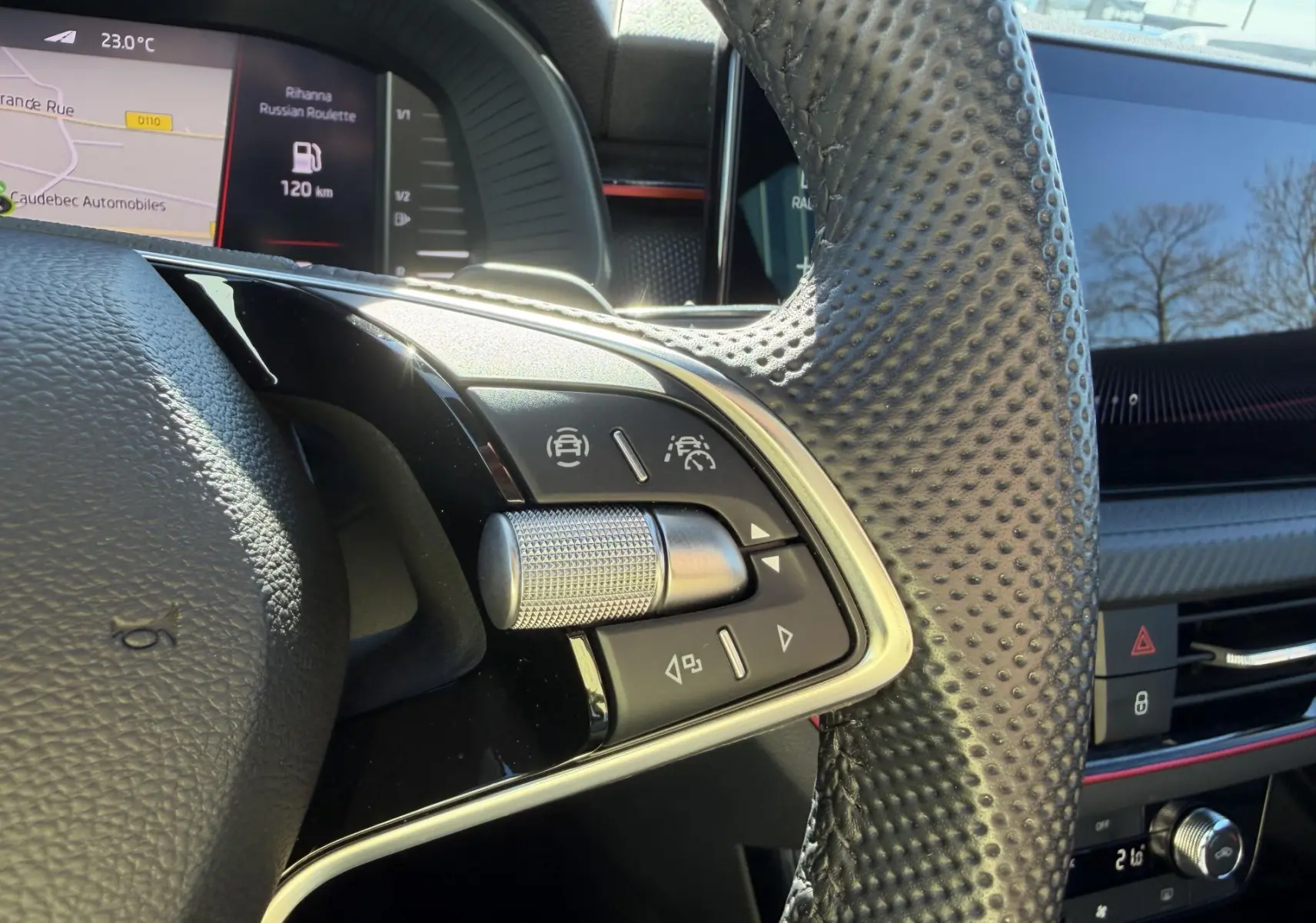 Gros plan sur le volant sport en cuir perforé du Skoda Kamiq 2025 avec commandes multifonctions et écran numérique en arrière-plan.