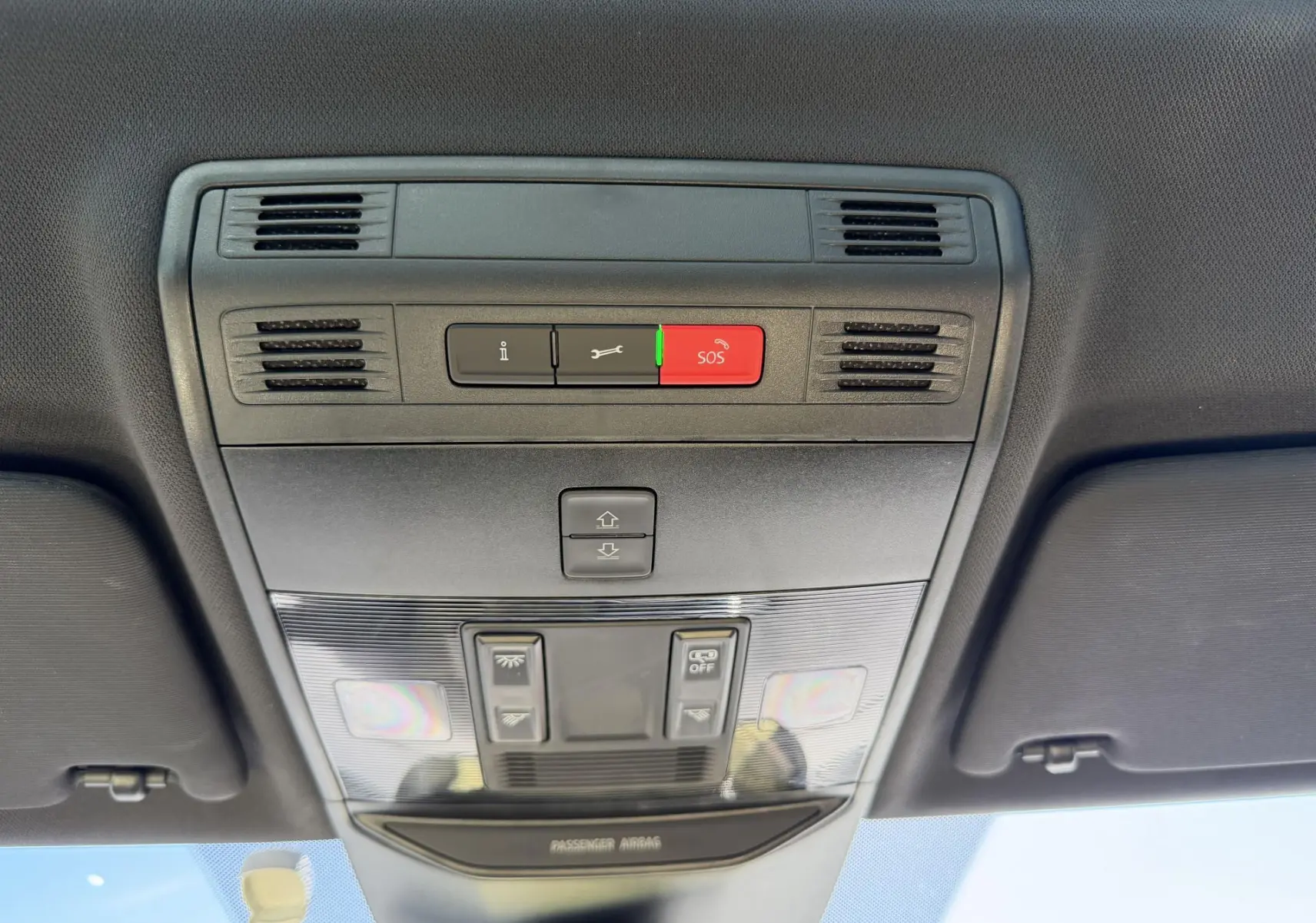 Vue en contre-plongée du plafonnier intérieur gris du Skoda Kamiq 2025 avec boutons SOS et commandes d’éclairage.