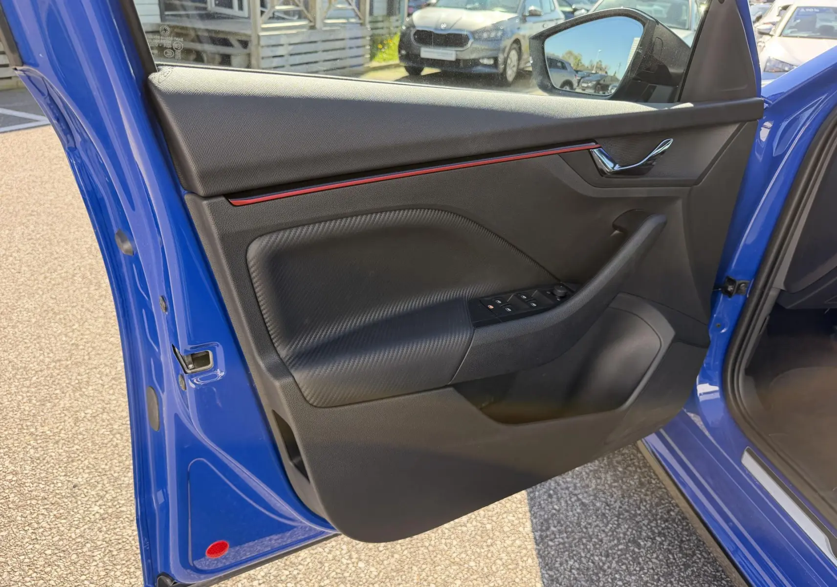 Vue intérieure de la porte avant gauche bleue du Skoda Kamiq 2025, avec garniture noire et bande décorative rouge.