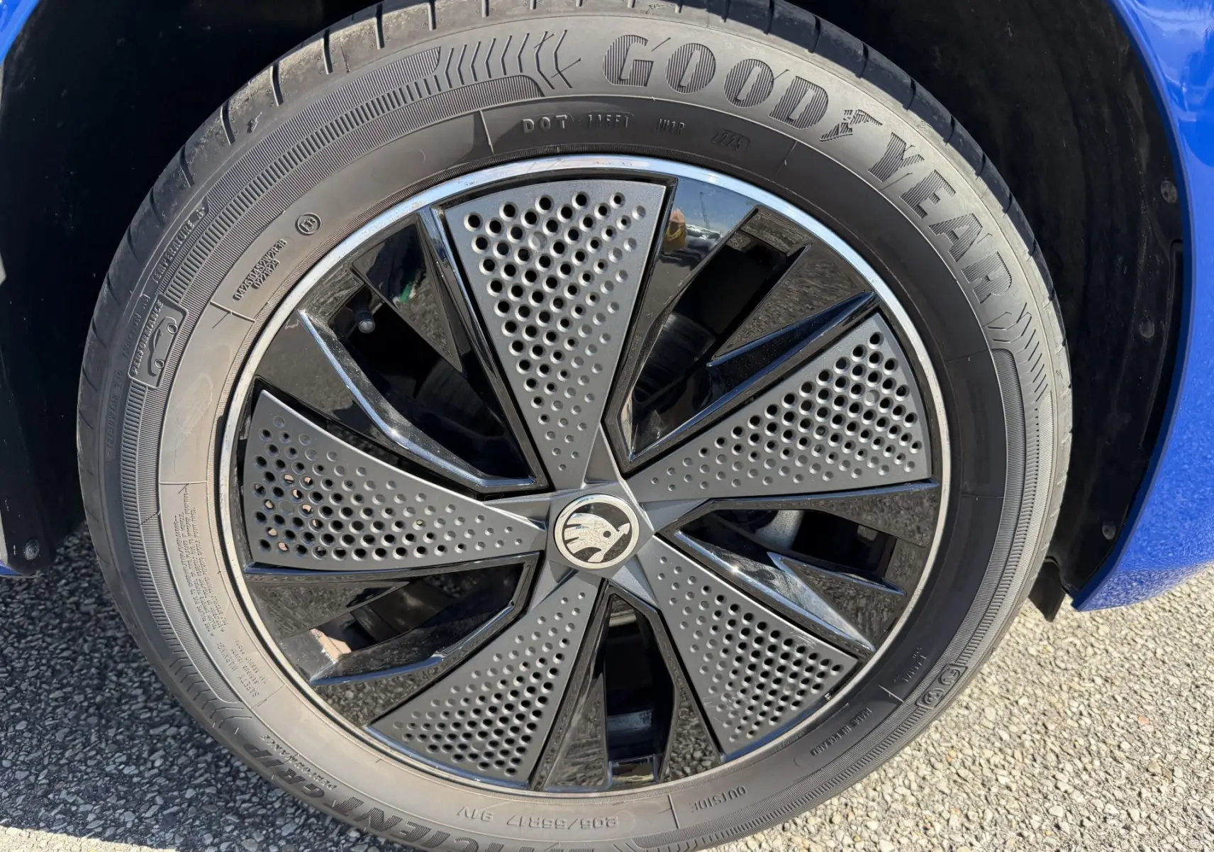 Gros plan sur la jante alliage noire 17 pouces du SKODA KAMIQ bleu, avec pneu Goodyear visible sur sol goudronné.