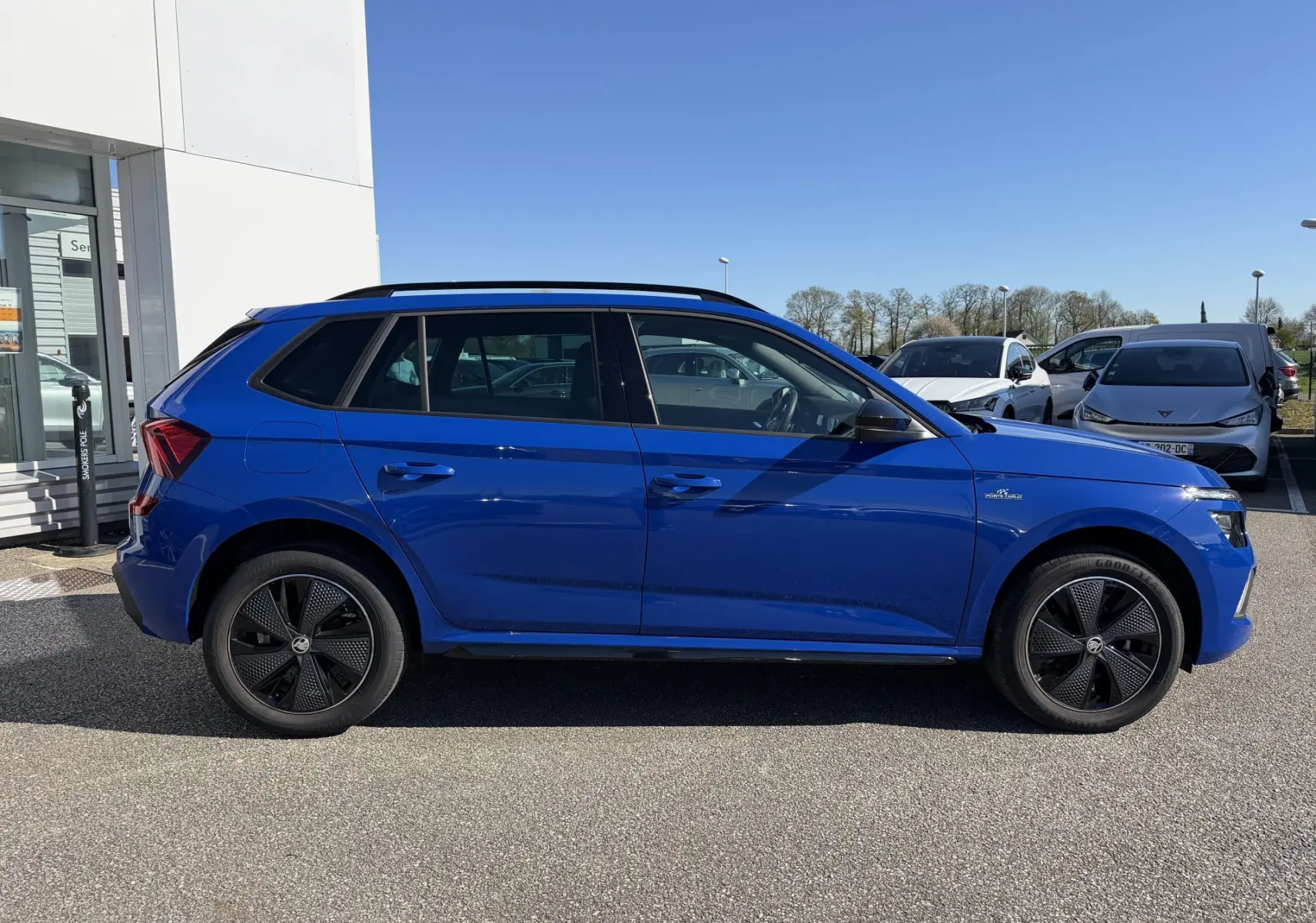 Vue de profil côté gauche d'un Skoda Kamiq bleu 2025 avec jantes alliage noires et badge TSI sur l'aile avant.