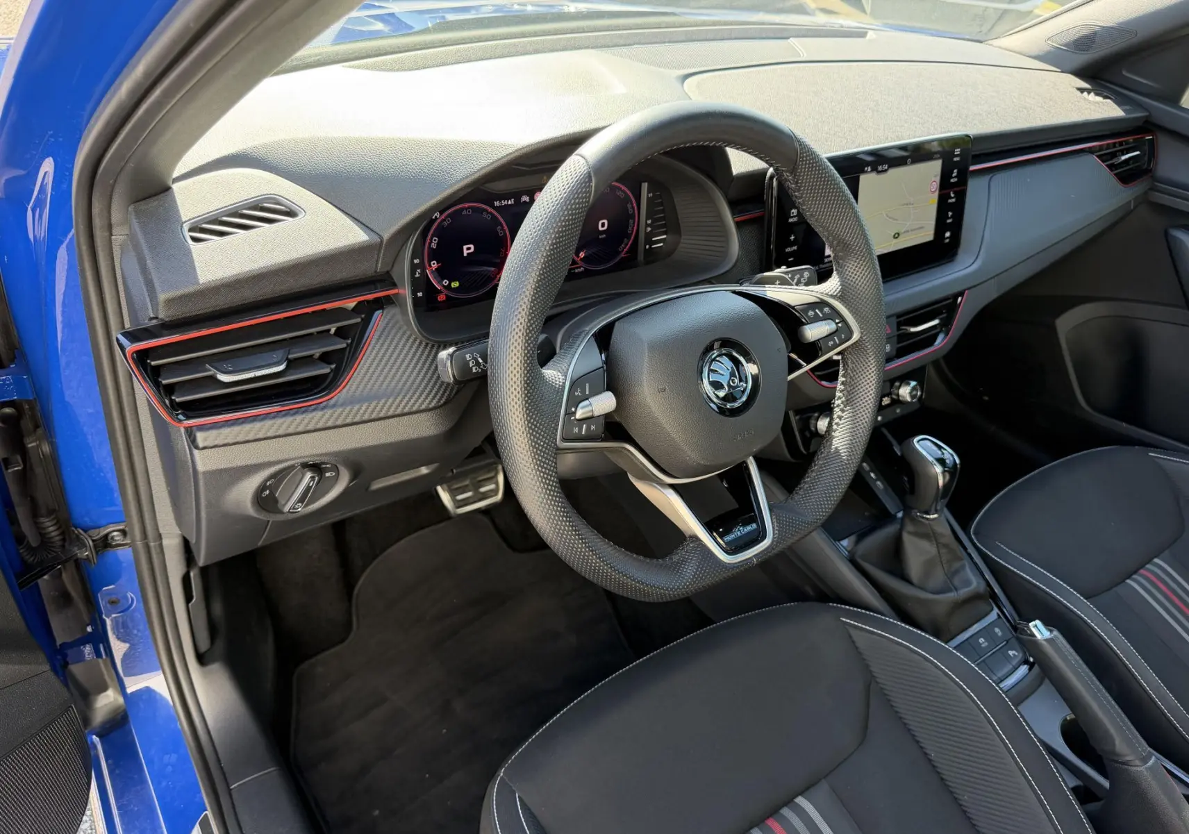 Vue intérieure côté conducteur du Skoda Kamiq bleu 2025, volant sport cuir, écran tactile 9,2 pouces et boîte manuelle.