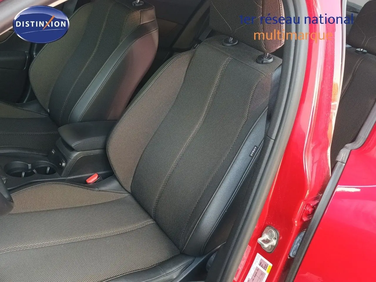 Vue intérieure côté conducteur sur les sièges en tissu et cuir noir du DS3 Crossback rouge métal avec porte ouverte.