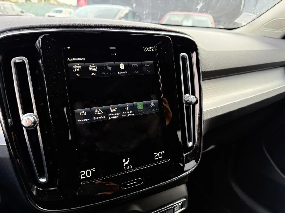 Écran tactile central noir du tableau de bord intérieur du Volvo XC40 Momentum blanc, affichant la climatisation à 20°C.