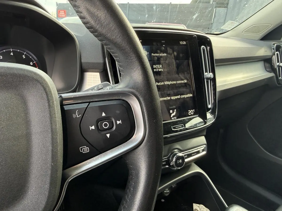 Vue intérieure du tableau de bord et volant cuir du Volvo XC40 Momentum 2020 essence, avec écran tactile central allumé.