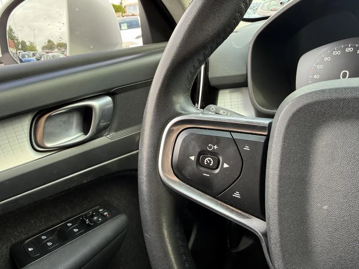 Détail du volant cuir et commandes au volant côté gauche dans l'habitacle du Volvo XC40 blanc.