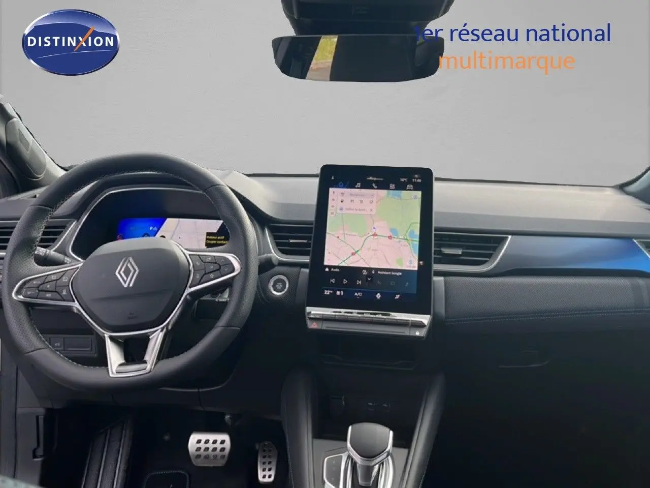 Vue intérieure frontale du tableau de bord de la Renault SYMBIOZ blanc nacré, avec écran tactile central et volant multifonction.