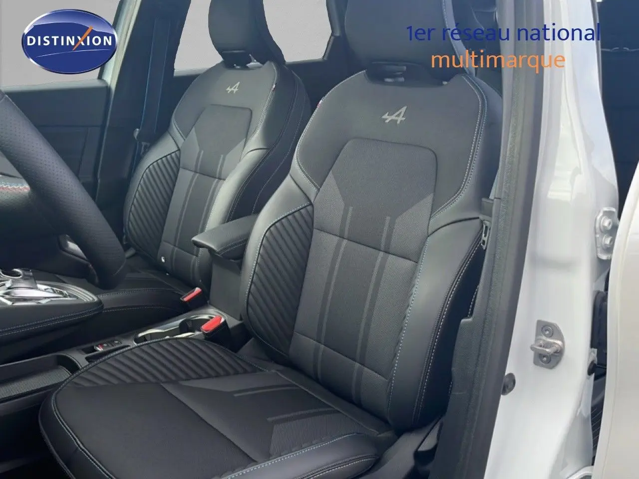 Vue intérieure côté conducteur du Renault Symbioz blanc nacré, sièges noirs avec logo Alpine brodé sur appuie-têtes.