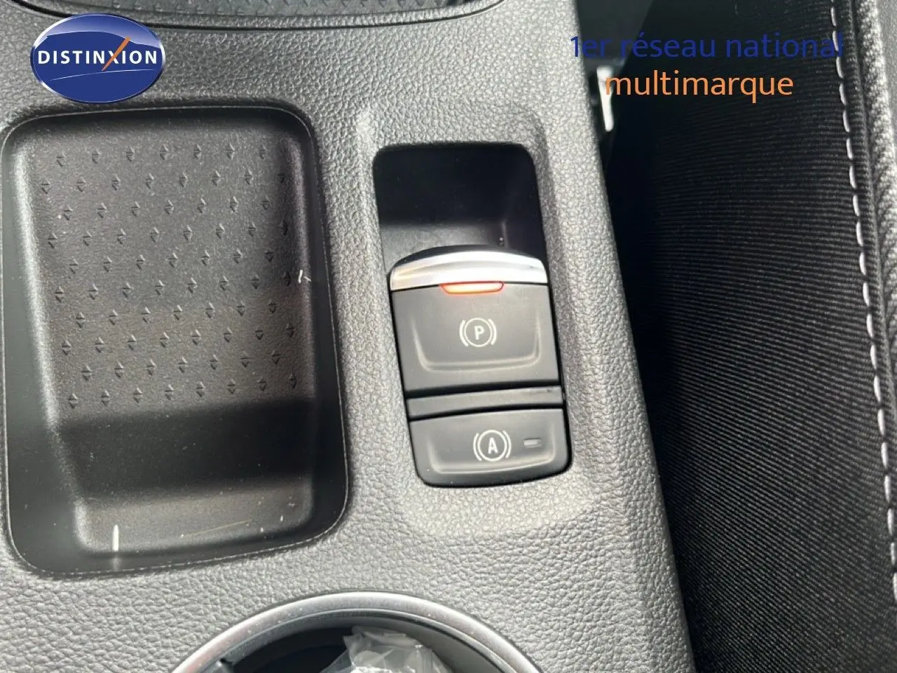 Gros plan sur la console centrale du Renault Symbioz blanc nacré, mettant en valeur les boutons de frein à main et auto start-stop.