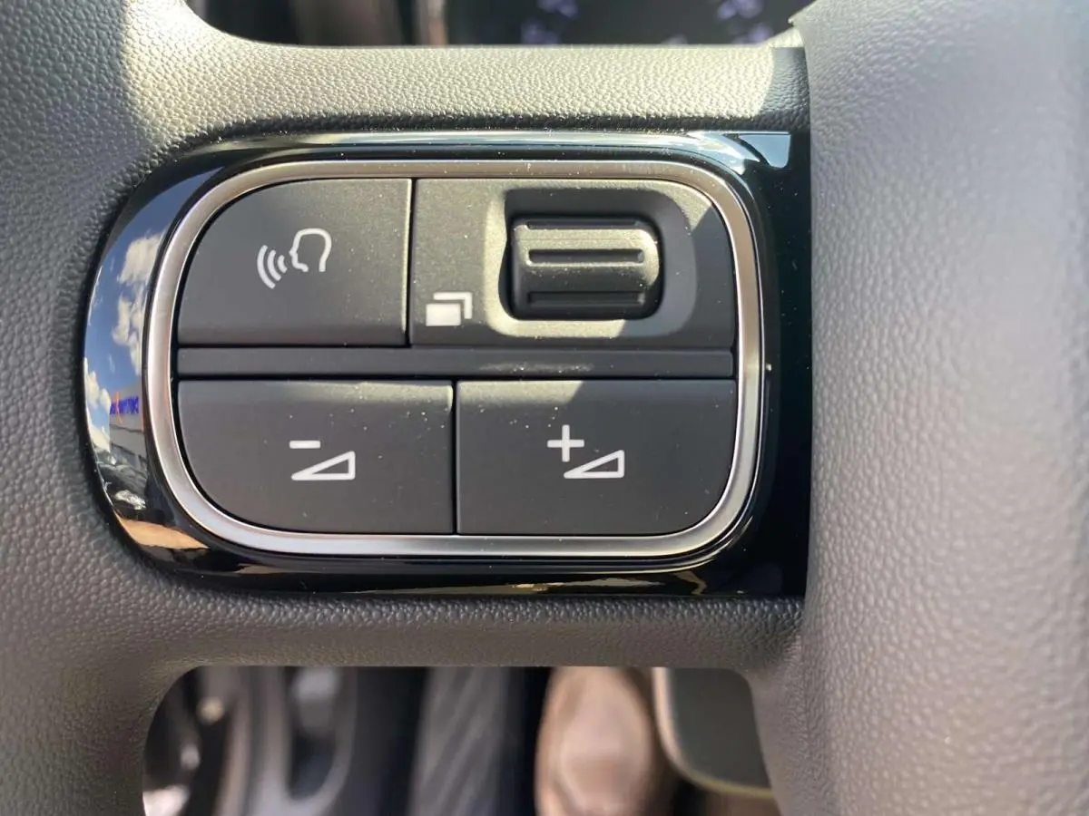 Gros plan sur les commandes de volume et de reconnaissance vocale sur le volant du Citroën C3 Aircross noir 2021.