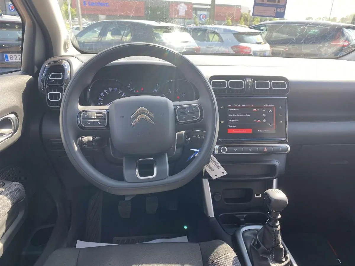 Vue intérieure frontale du tableau de bord noir du Citroën C3 Aircross 2021 avec volant, écran tactile et levier de vitesse manuel.