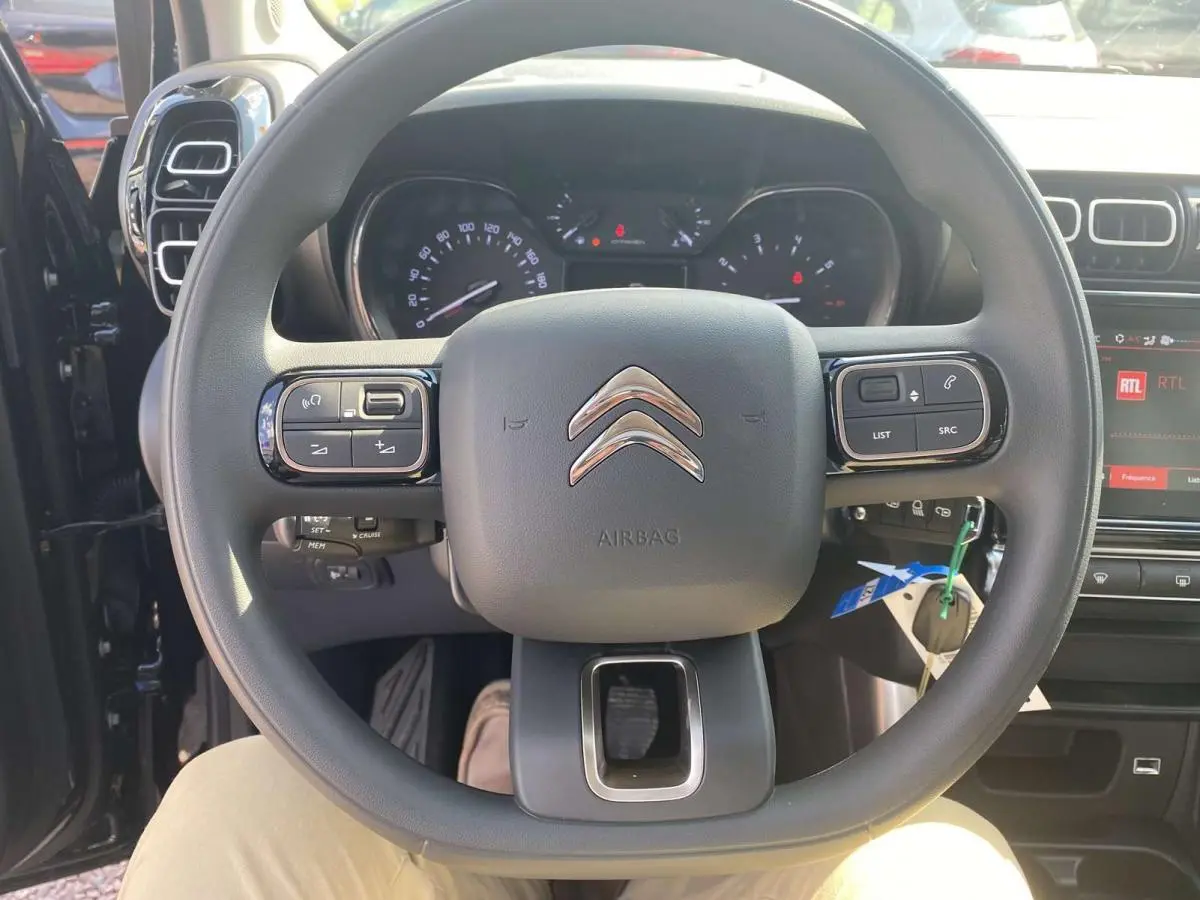 Vue rapprochée du volant noir de la Citroën C3 Aircross 2021, avec commandes intégrées et tableau de bord visible.
