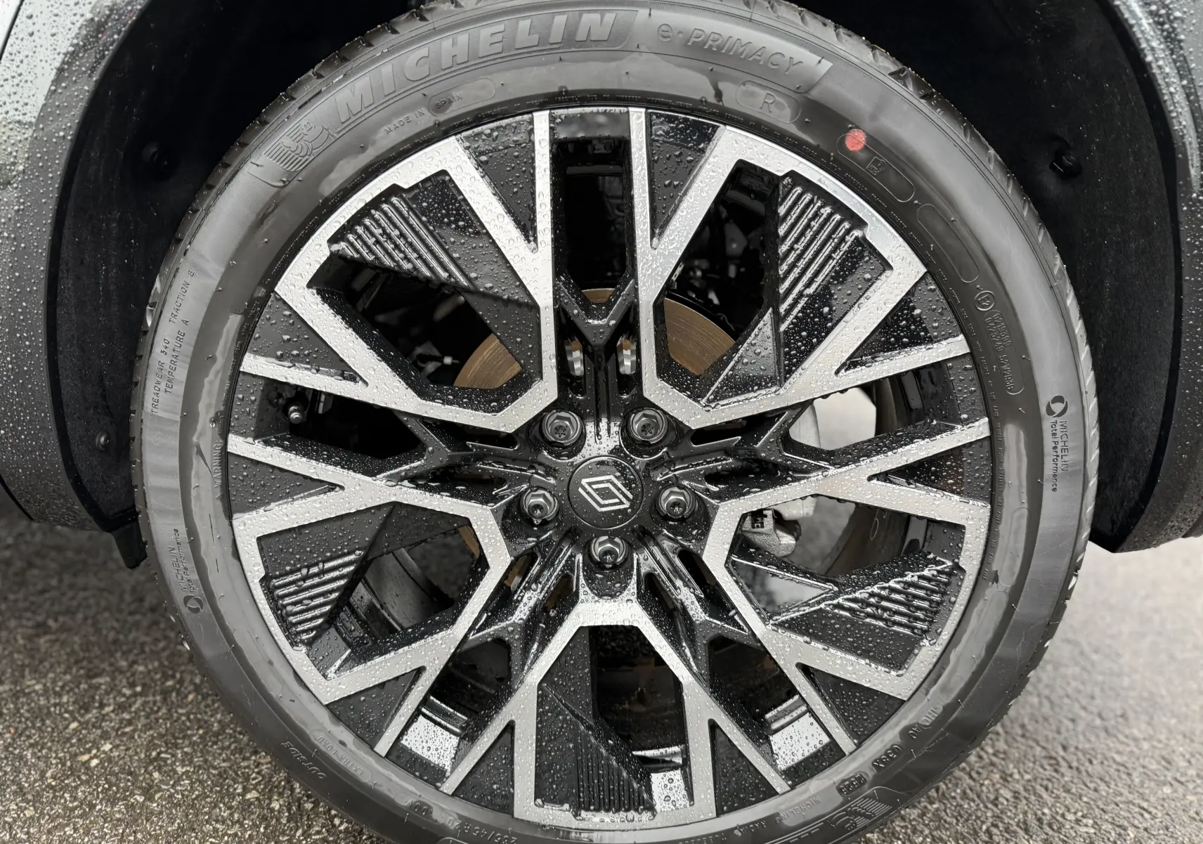 Gros plan sur la jante noire et argentée du Renault Austral 2025, avec pneus Michelin et gouttes d'eau visibles.